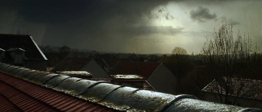 Ciel d'orage au-dessus des toits d'un village, faîtière humide au premier plan