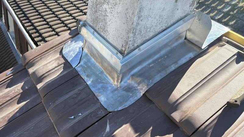 Habillage en zinc du pied d'une souche de cheminée sur une toiture en tuiles