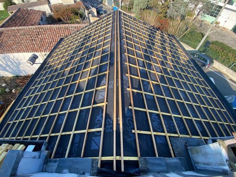 Toiture déposée vue d'en haut : écran de sous-toiture noir et liteaunage neuf sur toute la surface