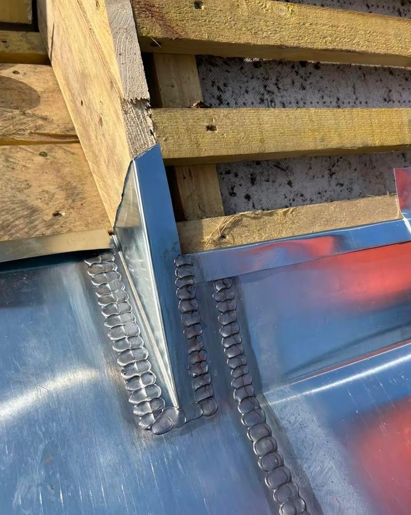 Soudure à l'étain d'un angle de noue en zinc, sous le liteaunage d'une toiture en rénovation